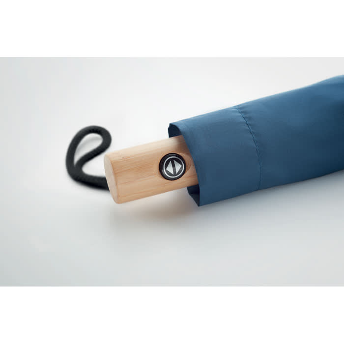 A blue umbrella with a wooden handle and a circular logo on the handle end.