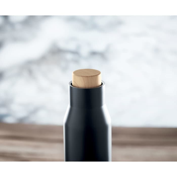 A drink bottle in matte black with a wooden top, set against a blurred background.