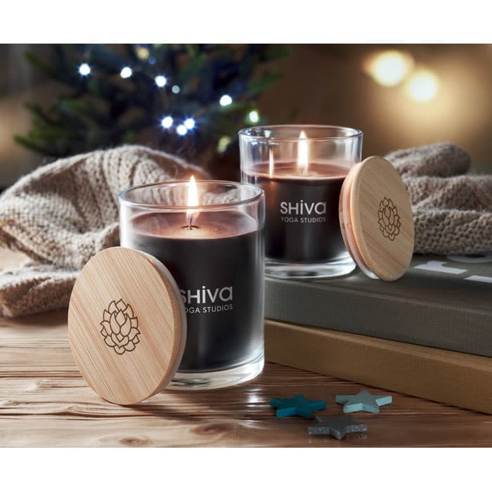 A candle set with black wax and wooden lids, placed beside a soft blanket and decorative stars.
