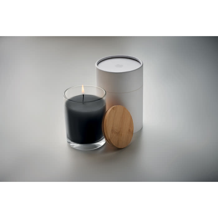 A candle in a glass holder with a black wax centre, accompanied by a white container and a wooden lid.