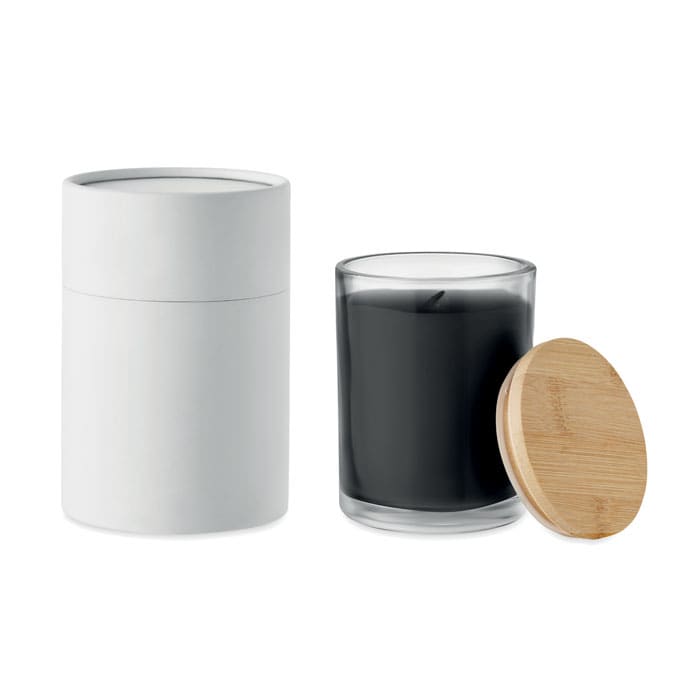 A candle in a clear glass holder with a black wax interior, accompanied by a white container and a wooden lid.