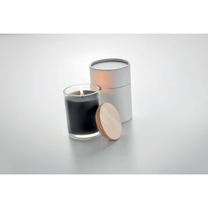 A candle in a glass jar with a wooden lid beside a sleek silver container. The candle is black.