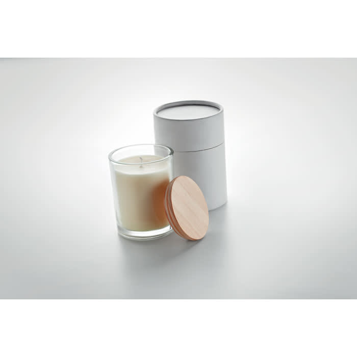 A glass candle with a wooden lid beside a cylindrical white container. The candle is creamy white.