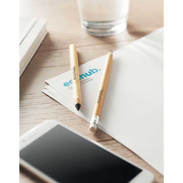 Two inkless bamboo pencils, one with a pencil tip and one with a stylus tip, resting on a blank sheet of paper.