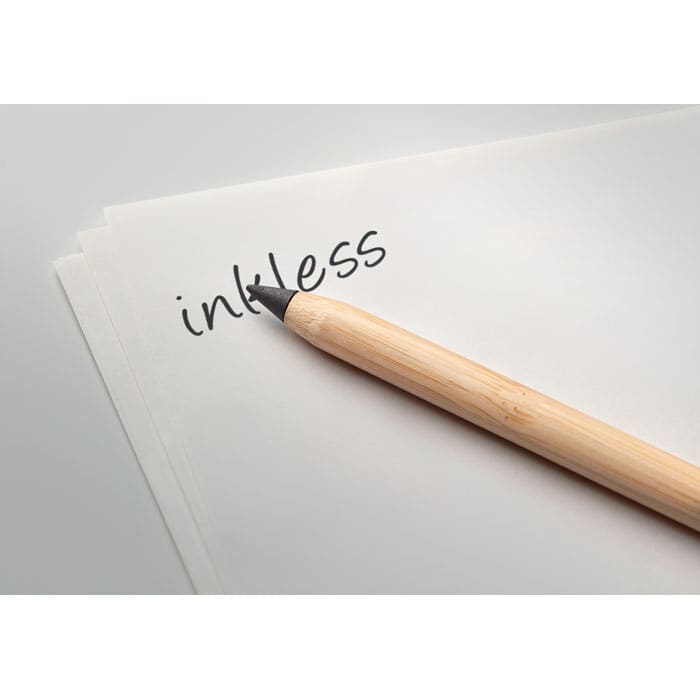 A bamboo pen rests on white paper with the word 'inkless' written on it. The pen has a natural finish.