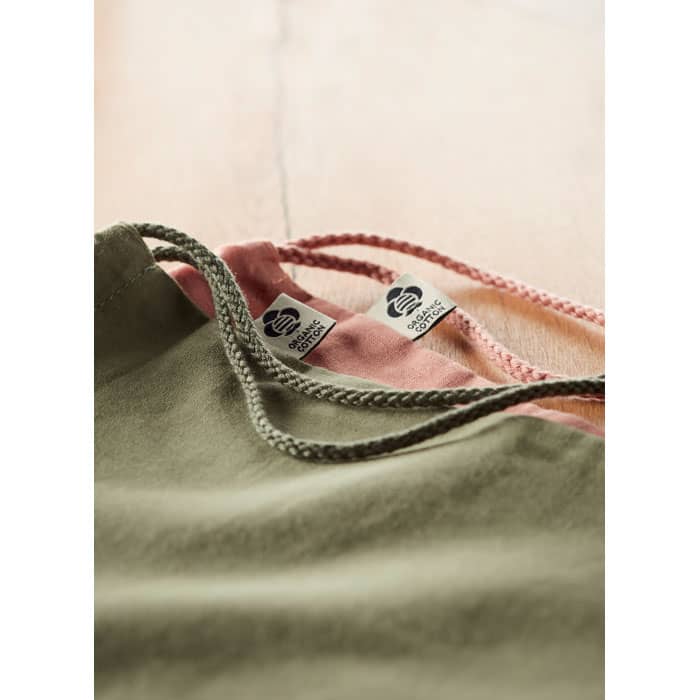 A clothing item featuring olive green and pink fabric, with decorative cords and branding labels visible.