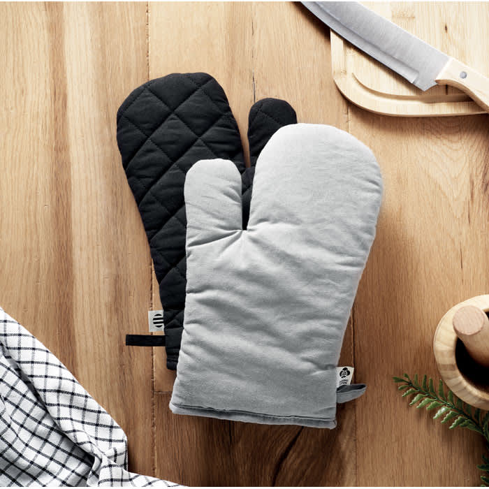 A pair of oven mitts featuring a black quilted design and a grey fabric finish, placed on a wooden surface.