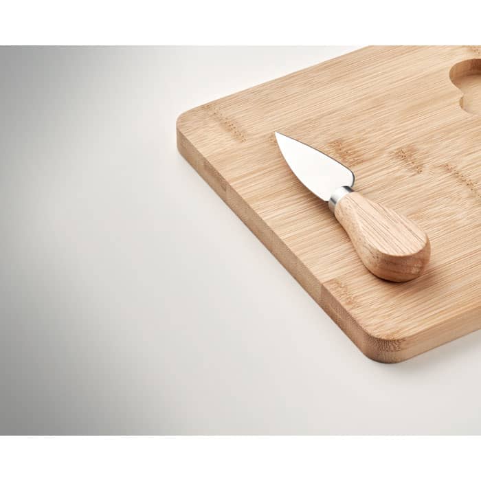 A wooden cutting board with a small knife featuring a wooden handle, placed on a smooth surface.