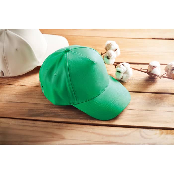 A green cap resting on a wooden surface, with a white cap visible in the background.