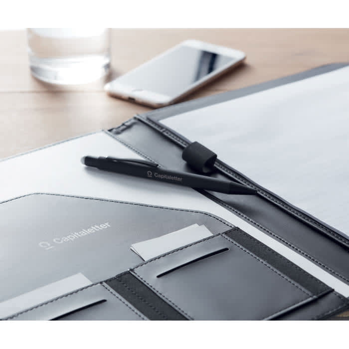 A black pen rests on a grey folder, with a glass of water and a smartphone in the background. The folder includes card slots.