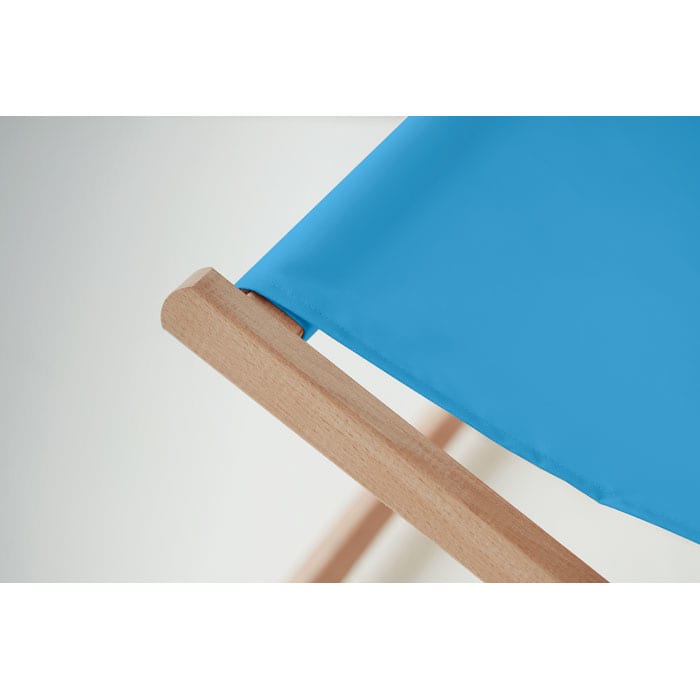 A blue folding chair with a wooden frame, focusing on the fabric and edge detail.