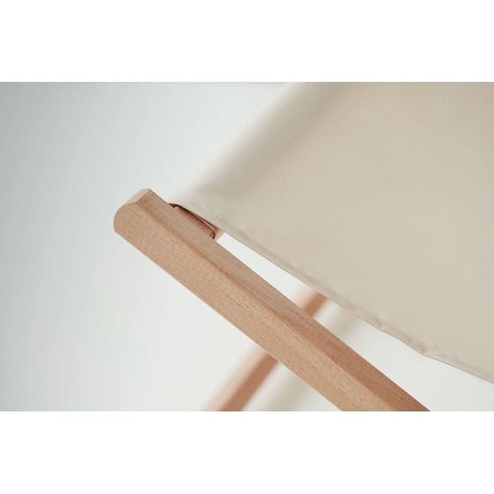 A close-up of a wooden chair frame with a beige fabric seat, highlighting the connection between materials.