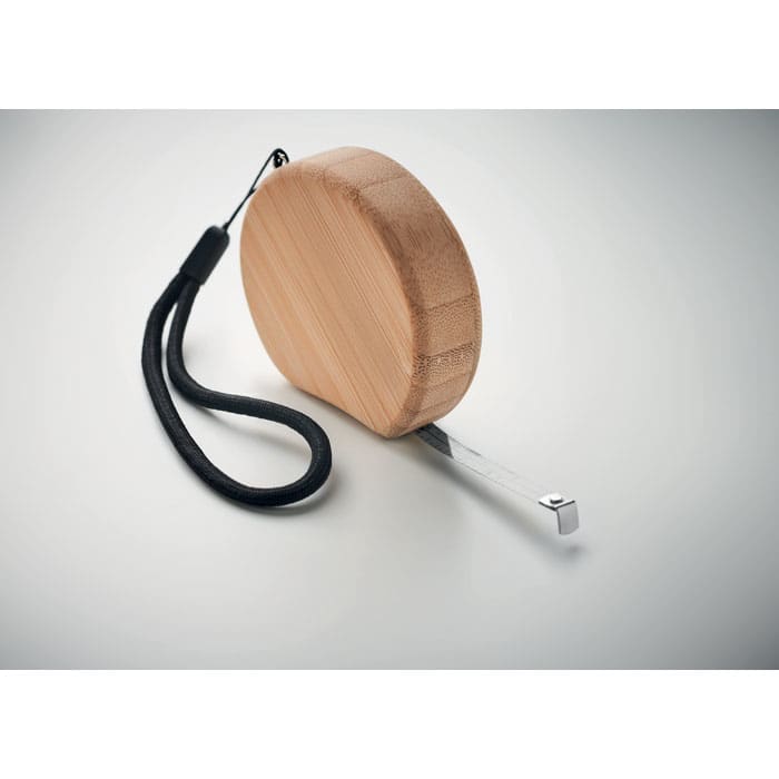 A measuring tape with a round bamboo casing and a silver metal blade attached to a black wrist strap.