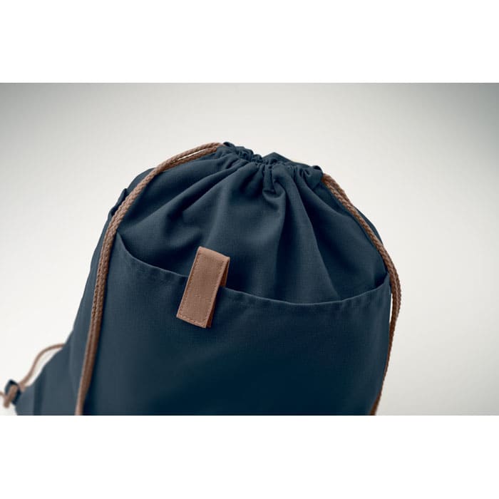 A navy drawstring bag with brown cord straps and a leather tab at the top. It has a simple, stylish design.