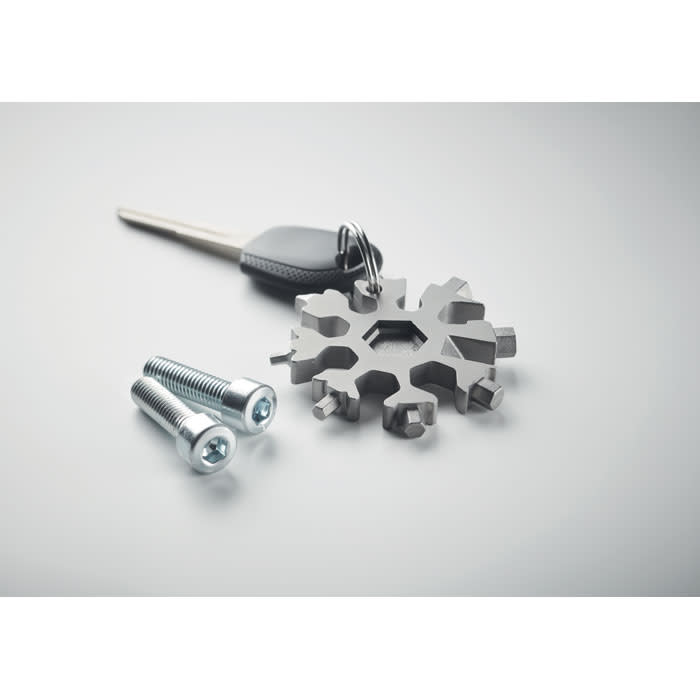 A silver multi-tool shaped like a snowflake, alongside two silver bolts and a black key.