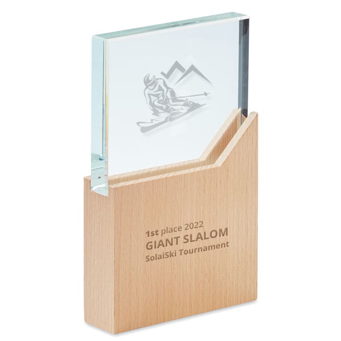 A trophy featuring a glass top with a skier etching and a wooden base. The design includes a mountain motif.