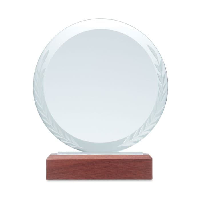 A round glass trophy with an engraved laurel wreath design, mounted on a wooden base.