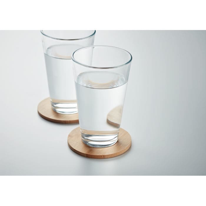 Two clear glasses filled with water, placed on round wooden coasters.