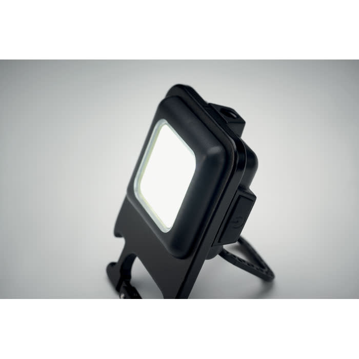 A portable LED light in a black casing, featuring a foldable stand and a simple on/off switch.