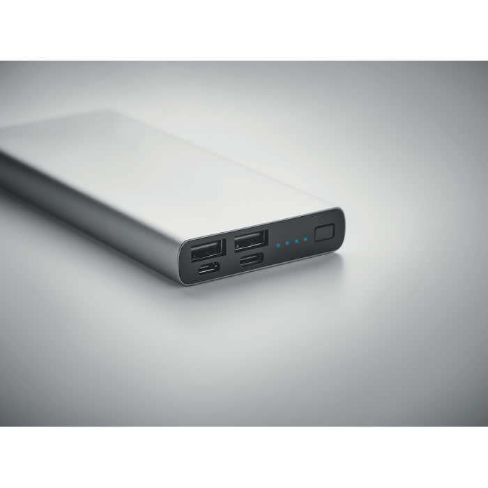 A power bank in a sleek silver design with multiple USB ports and an indicator light.