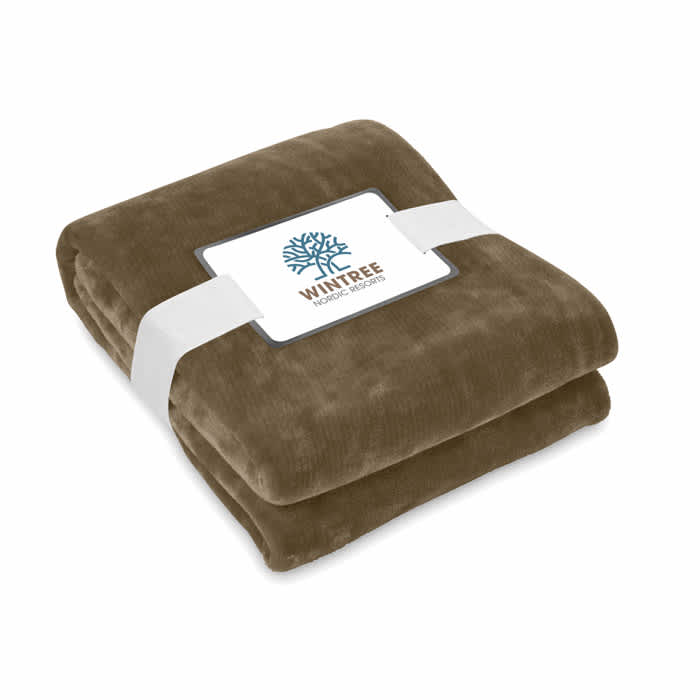 A folded brown blanket secured with a white band, featuring a logo on the packaging.