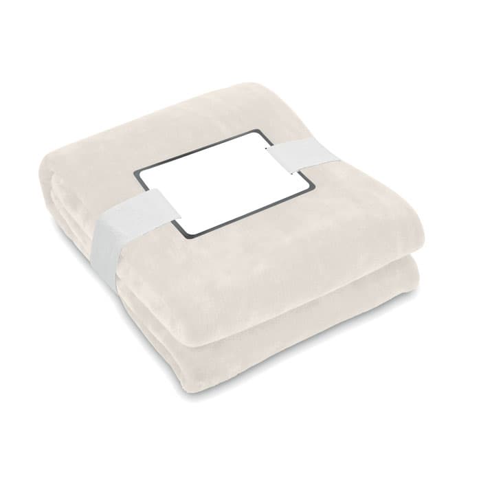 A soft, cream-coloured blanket neatly folded and secured with a white band, featuring a blank label.
