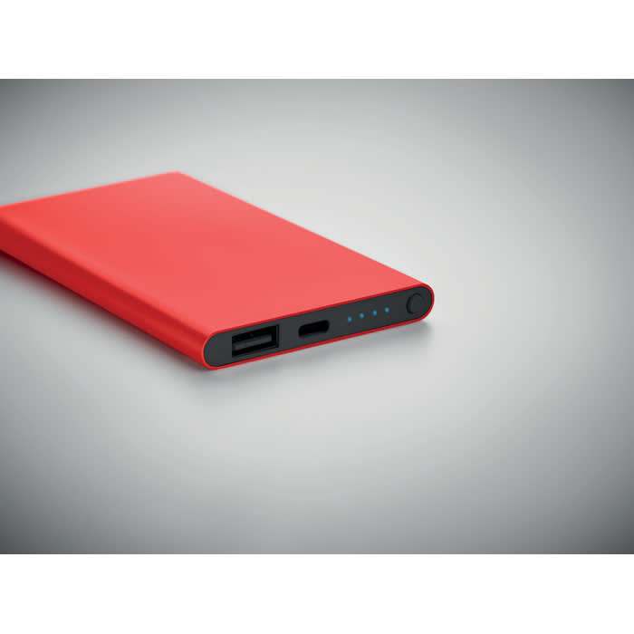 A red power bank with USB and USB-C ports, featuring an indicator light.