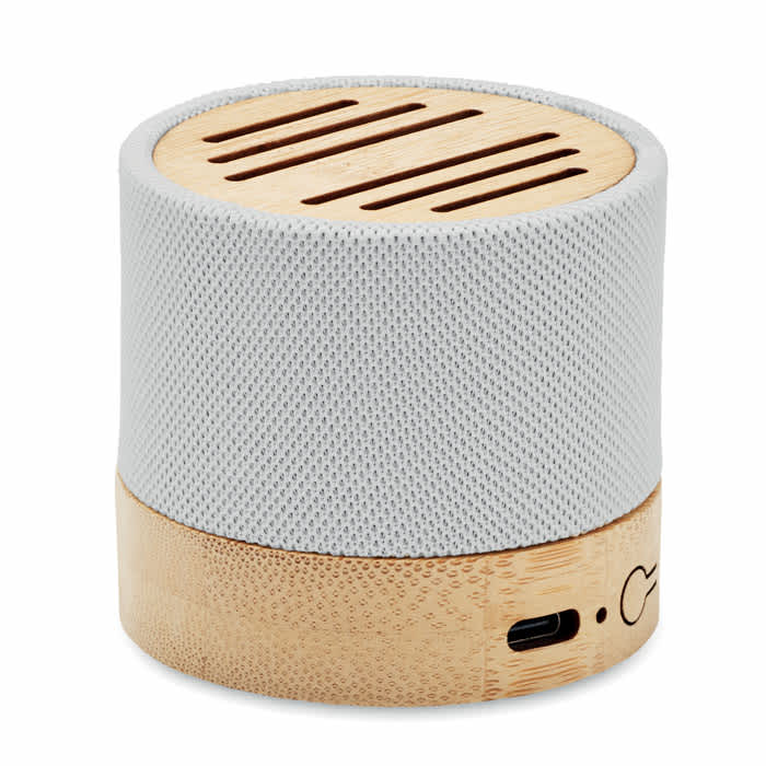 A portable speaker featuring a grey fabric exterior and a bamboo base, with ventilation slits on top.