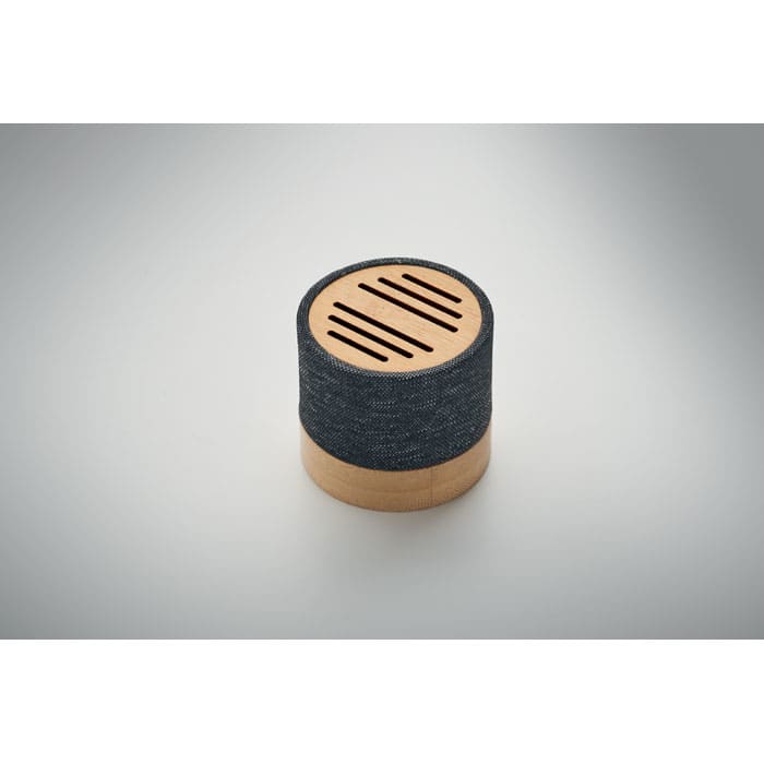 A round speaker with a black fabric exterior and a wooden base, featuring slotted openings on top.