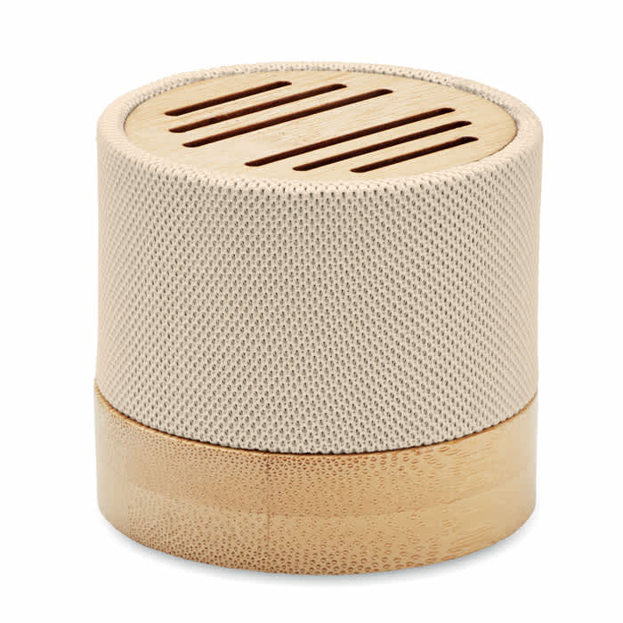 A round speaker with a beige mesh fabric cover and a wooden base, featuring slits on the top for sound projection.
