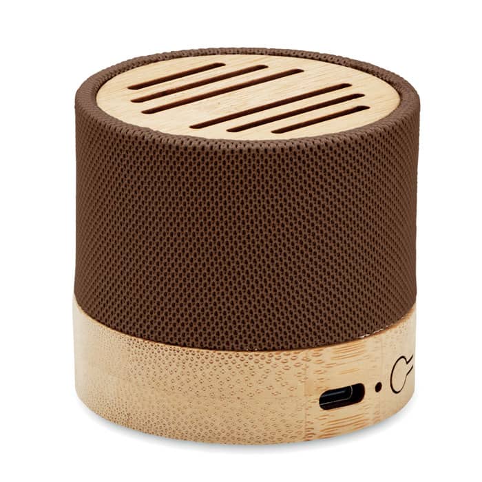 A small cylindrical speaker with a brown textured surface and a bamboo base. It features horizontal speaker vents on top.