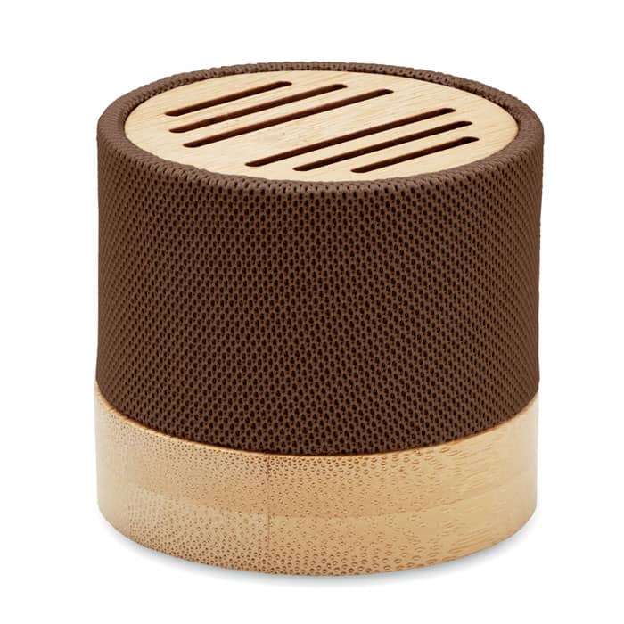 A compact speaker with a brown mesh exterior and a bamboo base, featuring ventilation slits on the top.