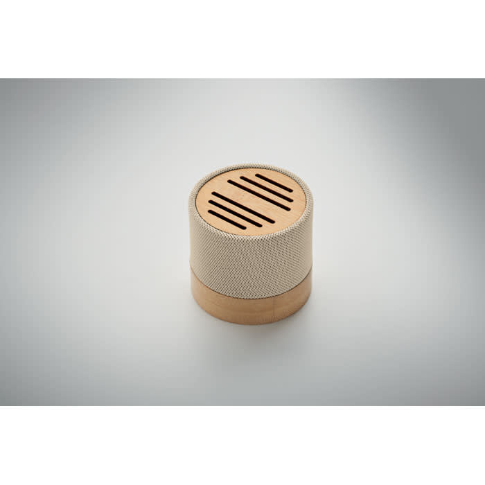 A round speaker with a beige fabric exterior and a wooden base, featuring slotted openings on the top.