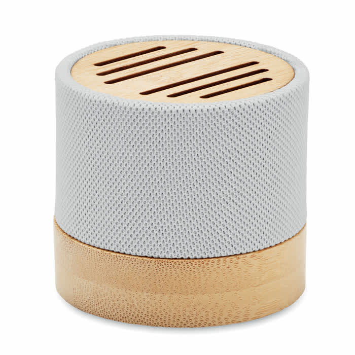 A round speaker with a grey mesh exterior and a light wood base, featuring slits on the top.