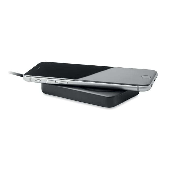 A wireless charger in black with a smartphone resting on top, connected by a cable. The design is sleek and minimalist.