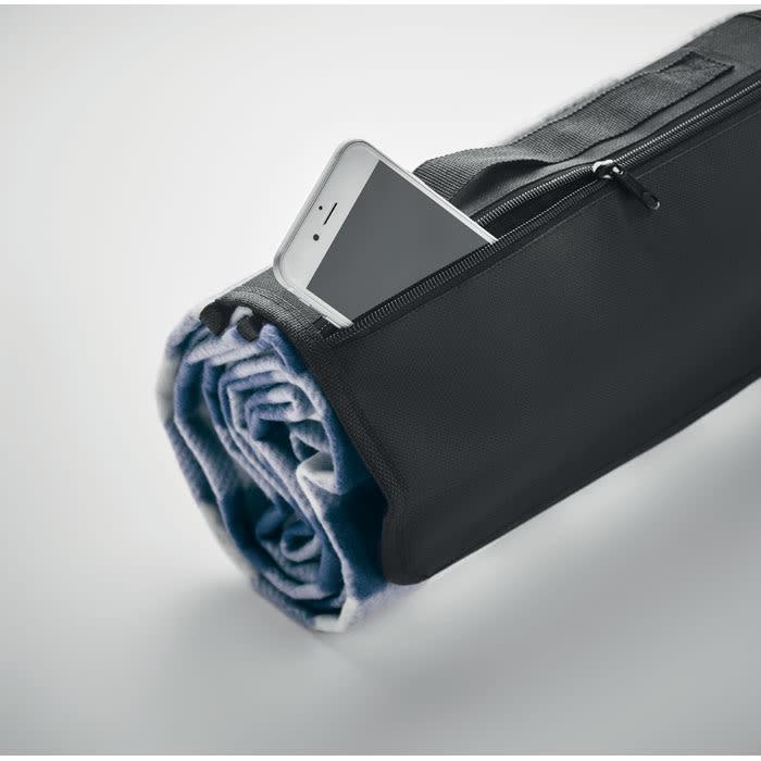 A rolled blanket in a black carry bag with a phone partially visible in the zippered pocket.