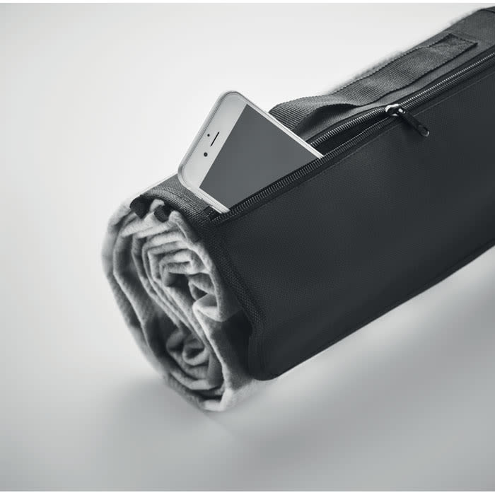 A rolled grey blanket with a black zipper bag, featuring a smartphone partially visible inside the pocket.