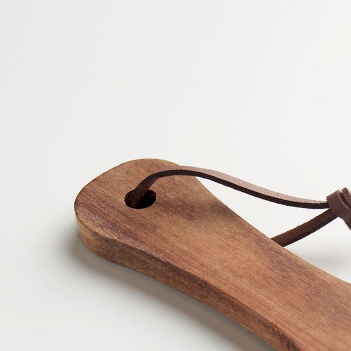 A wooden serving board with a leather strap, showcasing a natural finish and smooth surface.