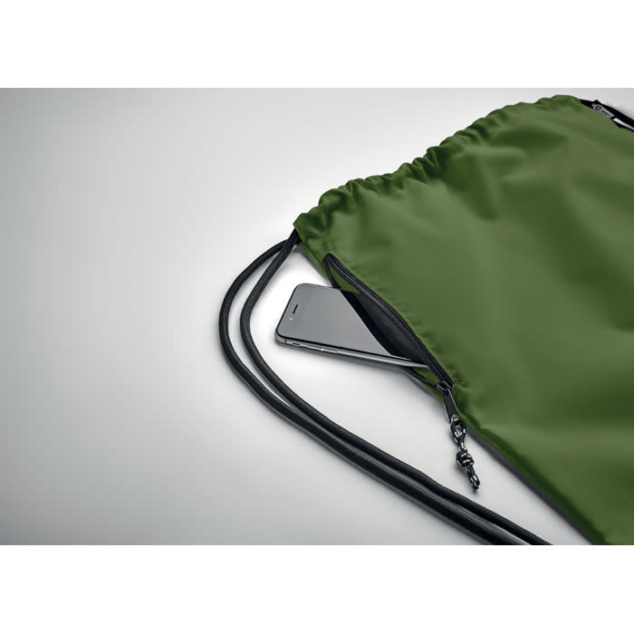 A drawstring bag in olive green, partially unzipped with a phone peeking out from inside. It has a logo.