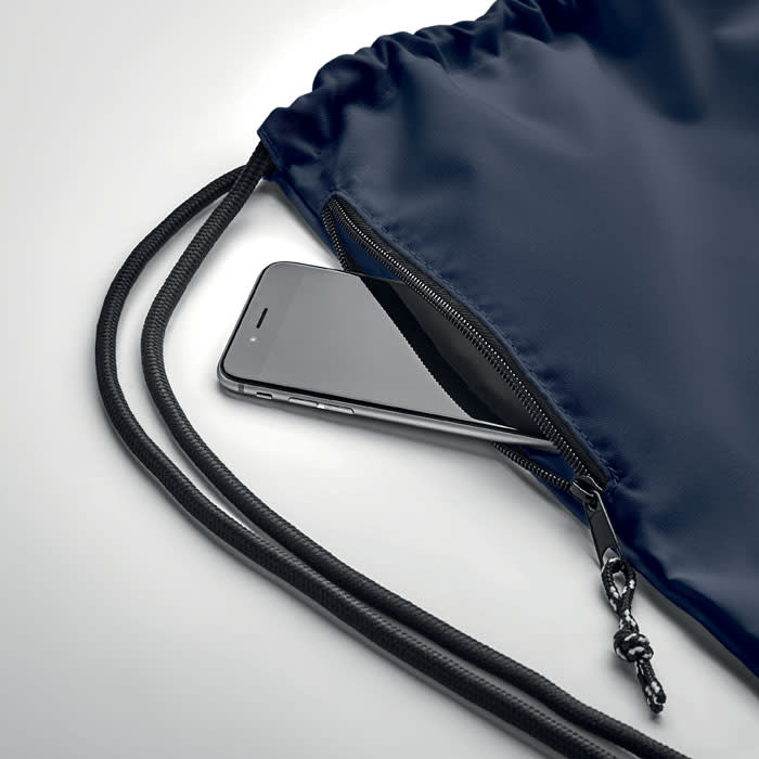 A navy drawstring bag with a smartphone partially tucked inside a zippered pocket.