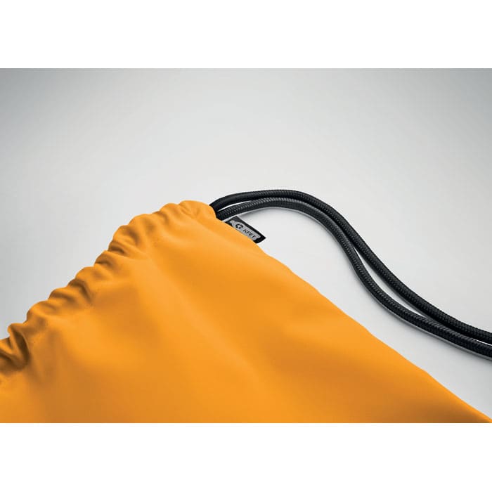 A drawstring bag in vibrant orange, featuring black cords and a tag with branding.
