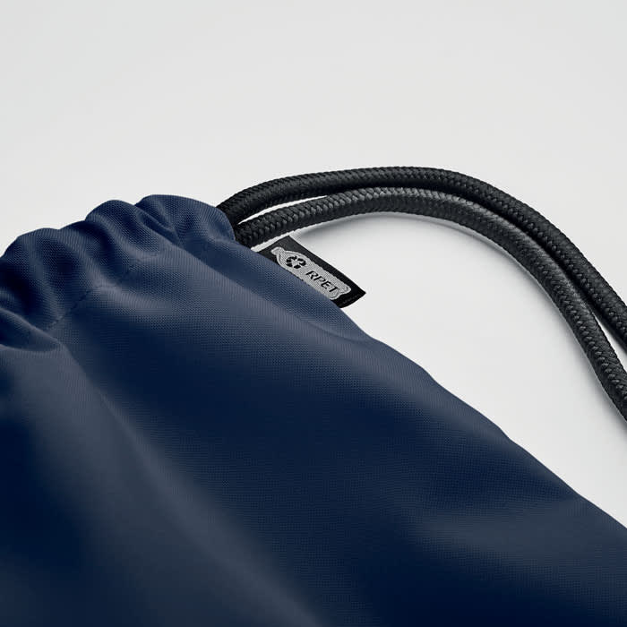 A drawstring bag in navy blue with a textured finish and black cord straps. It includes a small logo tag.