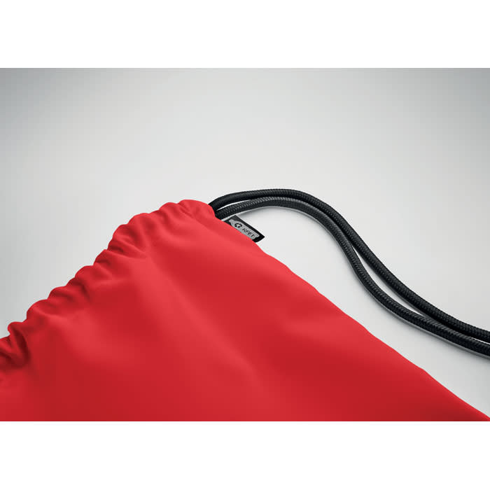 A drawstring bag in vibrant red with black cords and a small logo tag.