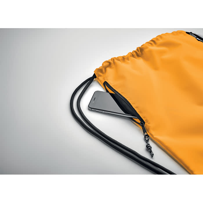 A drawstring bag in vivid yellow with a black cord, featuring a smartphone peeking from the zippered pocket.
