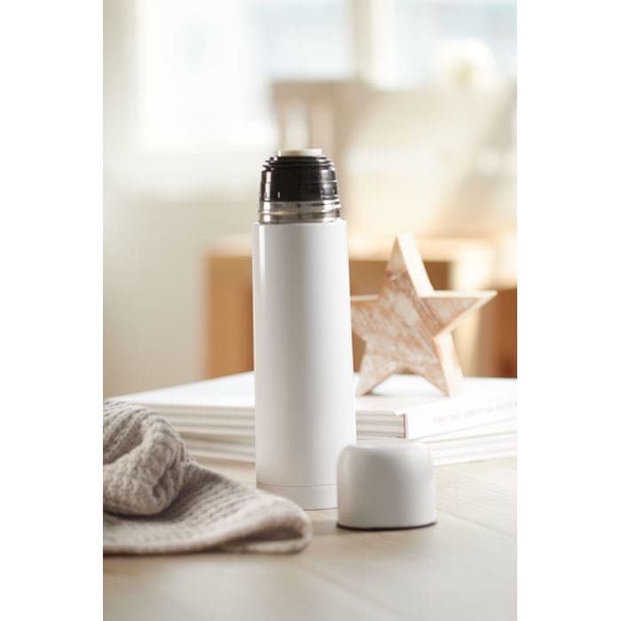 A drink bottle in white with a silver top, accompanied by a matching white lid, on a wooden surface.