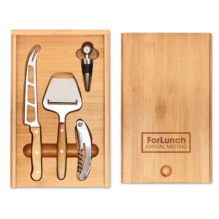 A wooden box containing cheese knives, a corkscrew, and a wine stopper, with a logo on the lid.