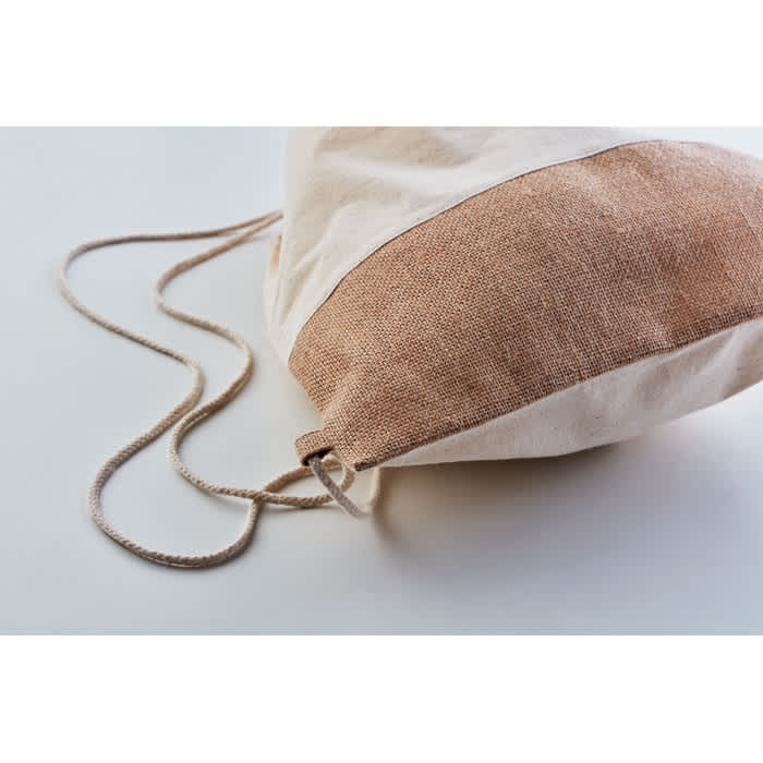 A drawstring bag in cream and light brown fabric with a natural-coloured cord. It has a simple design and texture.
