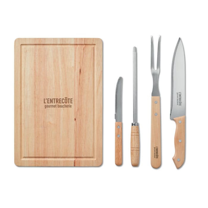 A wooden cutting board with a knife, fork, honing steel, and carving knife, all featuring wooden handles.