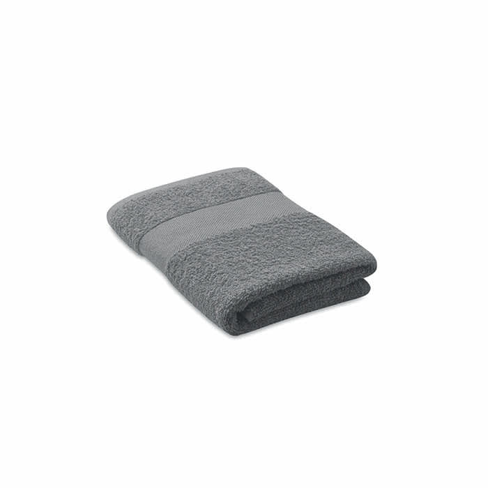 A folded grey towel with a textured and smooth stripe design, featuring a subtle logo.