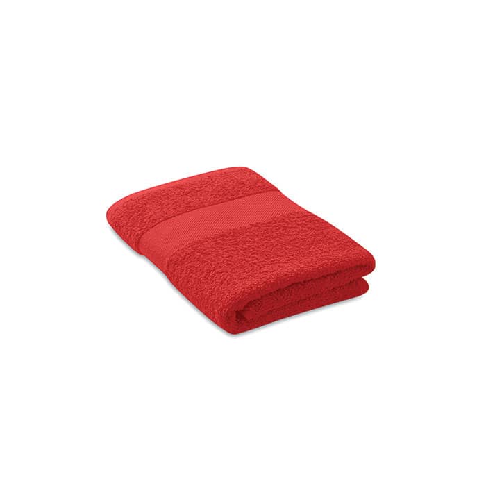 A folded red towel featuring textured lines, with a soft, plush appearance. It has a branded logo visible.